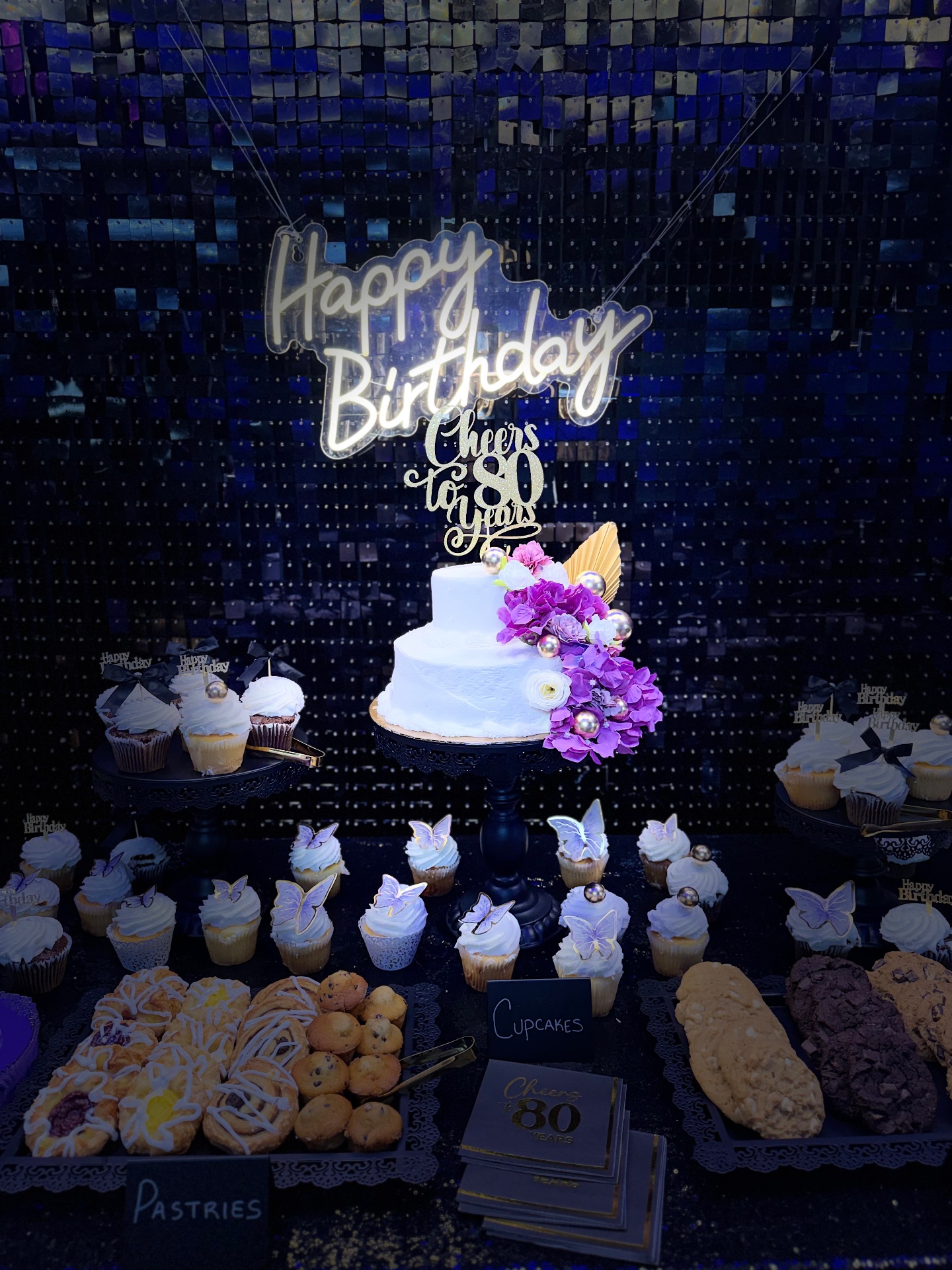 Cheers to 80 Years dessert table with cake and cupcakes