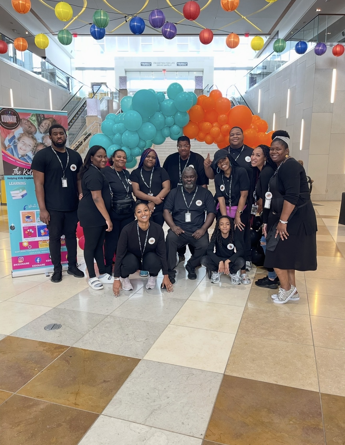 Team gathered at a vibrant community celebration with colorful balloon decor